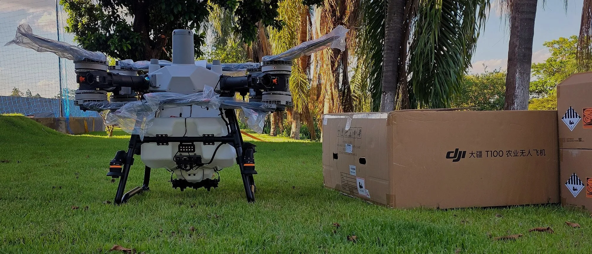 DJI Agras T100 recém-chegado, ainda com a película de proteção, ao lado da caixa original