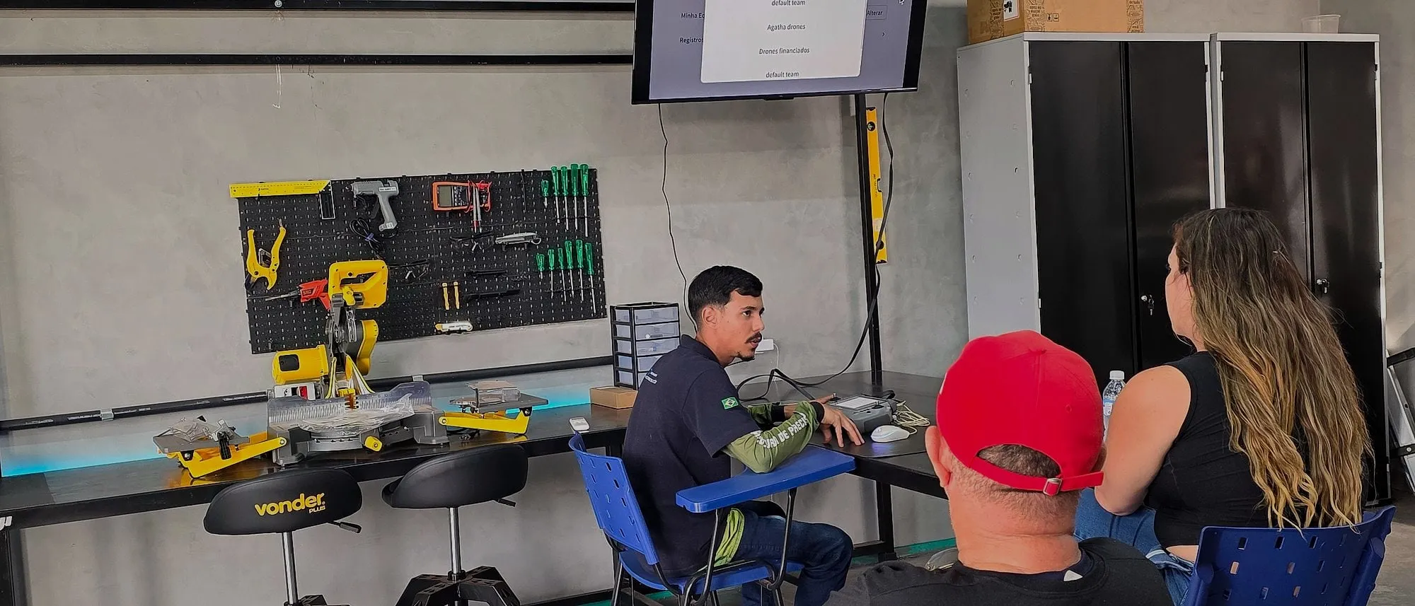 Alunos sentados diante da TV em aula no laboratório da Drone Sense