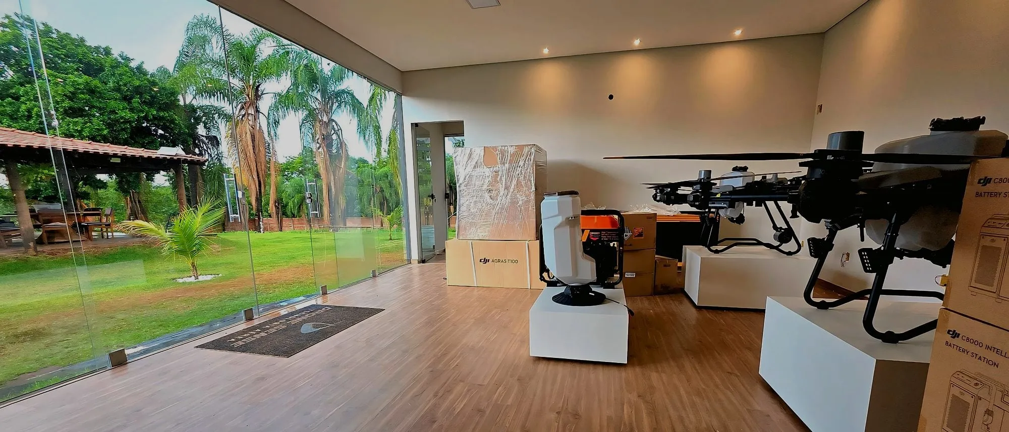 Drones DJI Agras expostos no showroom da Drone Sense, com caixas do T100 ao fundo