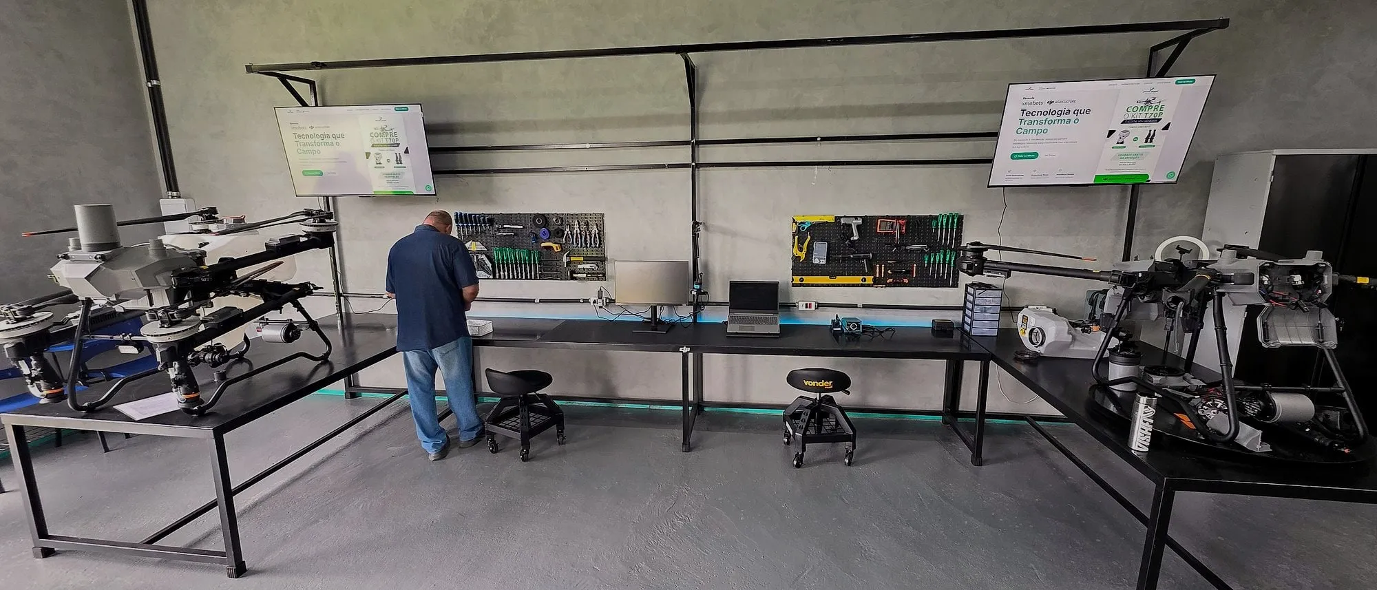 Técnico na bancada do laboratório da Drone Sense, com drones DJI Agras sobre as mesas