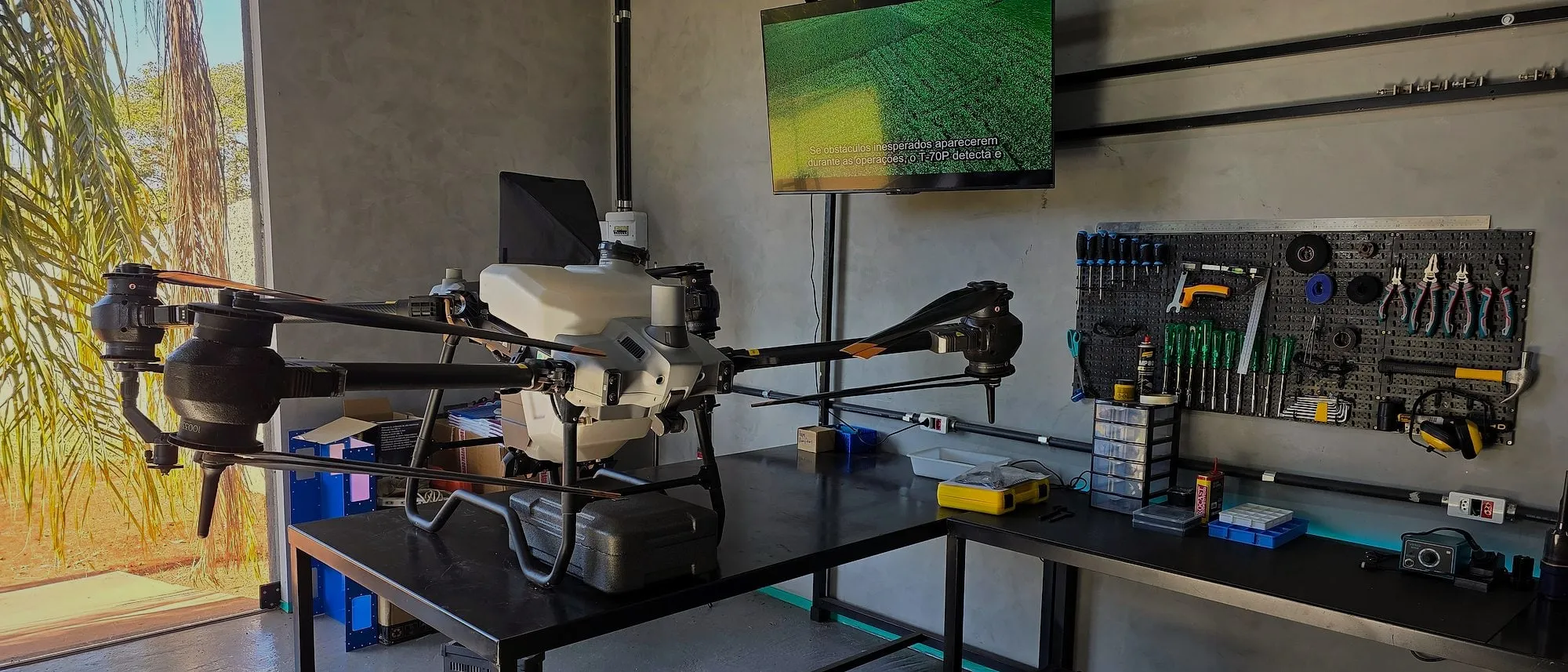 DJI Agras sobre a bancada do laboratório da Drone Sense, com o painel de ferramentas ao fundo