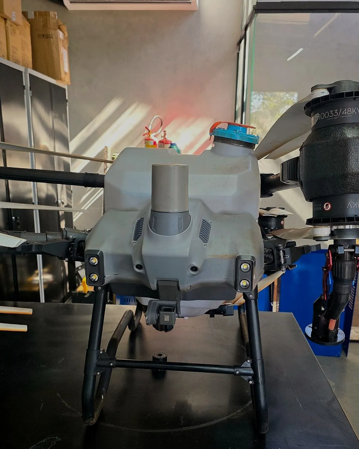 Tanque de calda do DJI Agras visto de perto, sobre a bancada do laboratório da Drone Sense