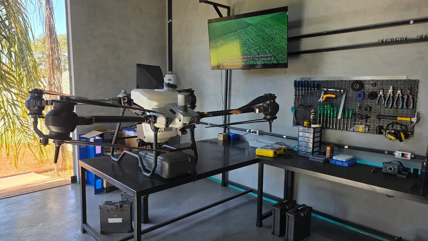 Drone Agras na bancada do laboratório Drone Sense, com ferramentas e baterias