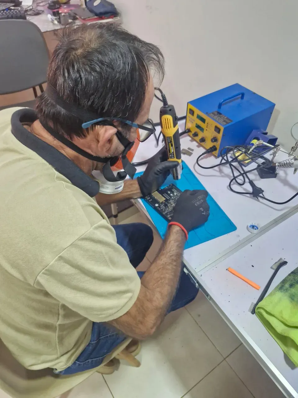 Técnico trabalhando com uma placa eletrônica na bancada de reparo de baterias